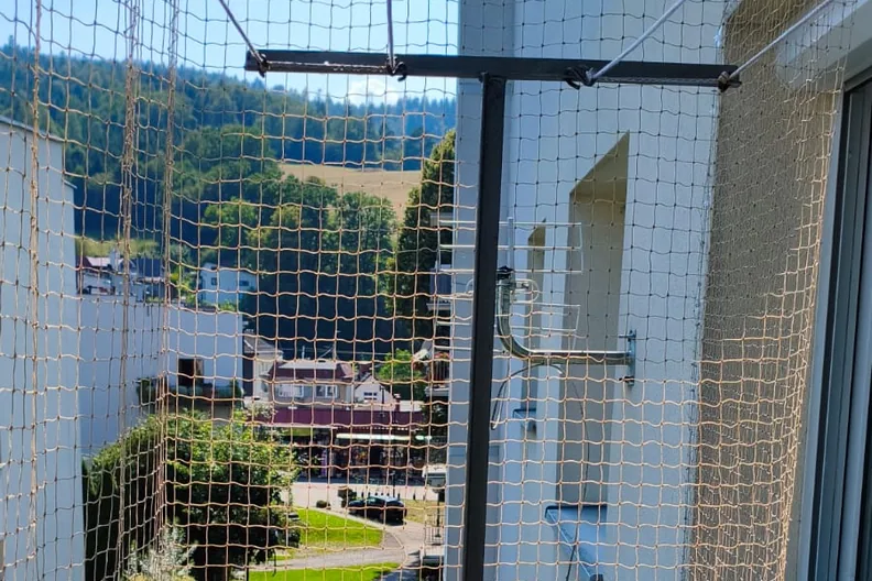 Siatka na boku balkonu przy oknie, na zaczepach klejonych - zabezpieczenie balkonu dla kota